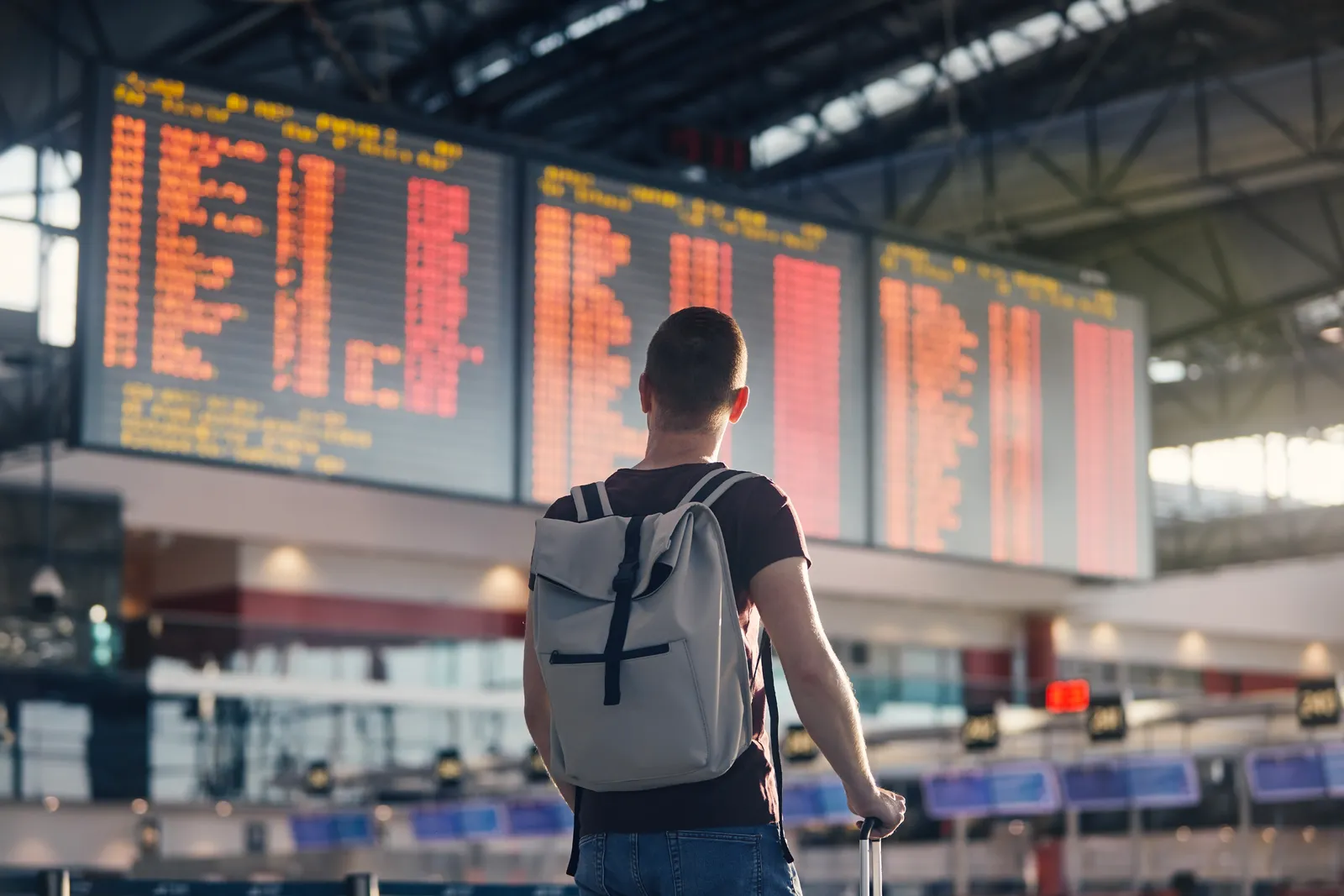 Viajante observa o painel de partidas num aeroporto — transferes de táxi de Caminha para os aeroportos do Porto, Vigo e Lisboa · Táxi Afonso 06