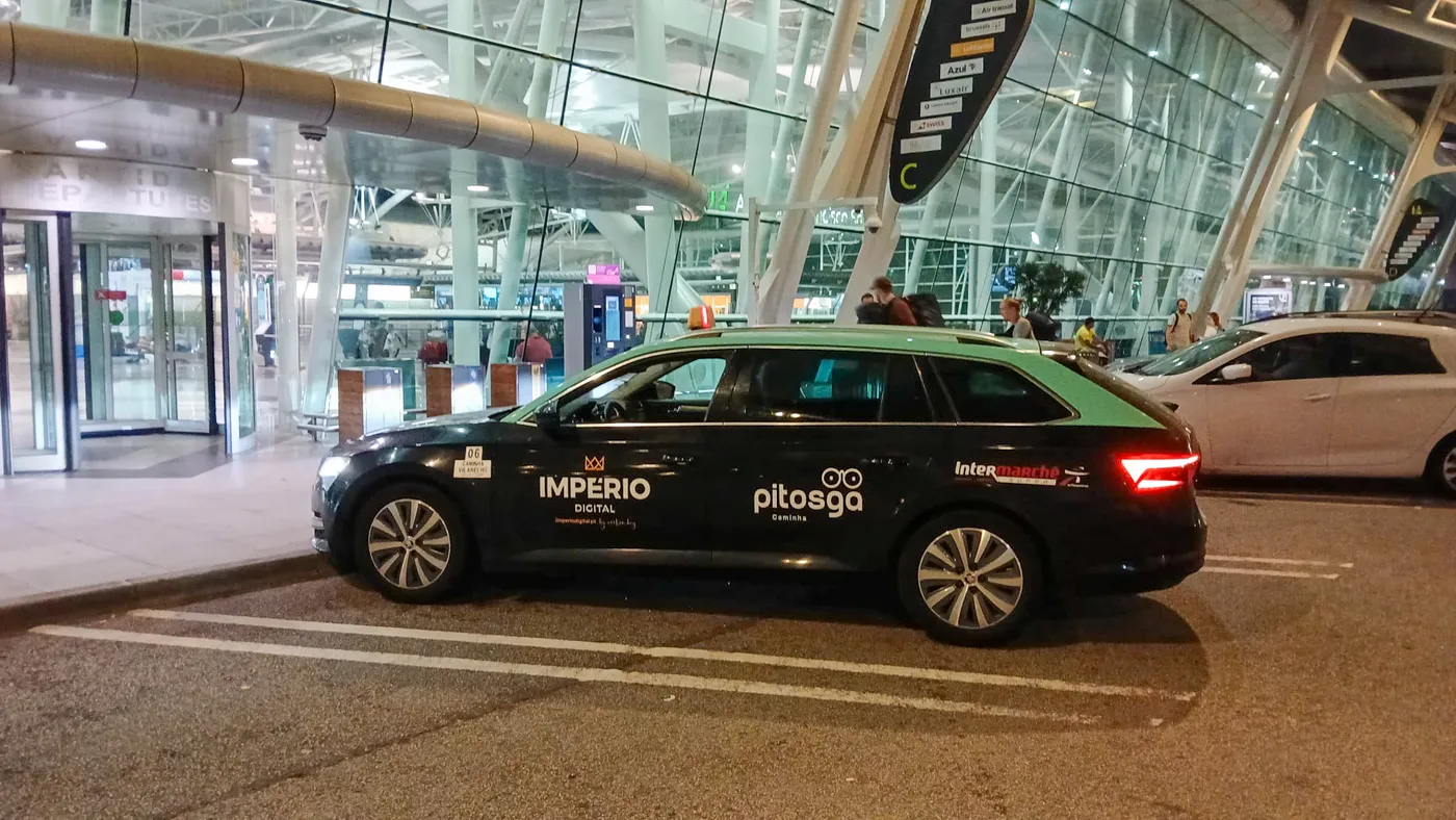 Táxi Afonso 06 de Caminha junto ao terminal do Aeroporto do Porto, à noite — transferes de aeroporto a preço fixo