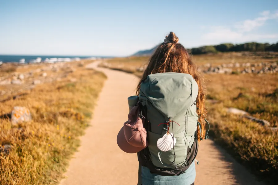 Peregrina com mochila num caminho costeiro — apoio Caminho da Costa · Táxi Afonso · 06 Caminha